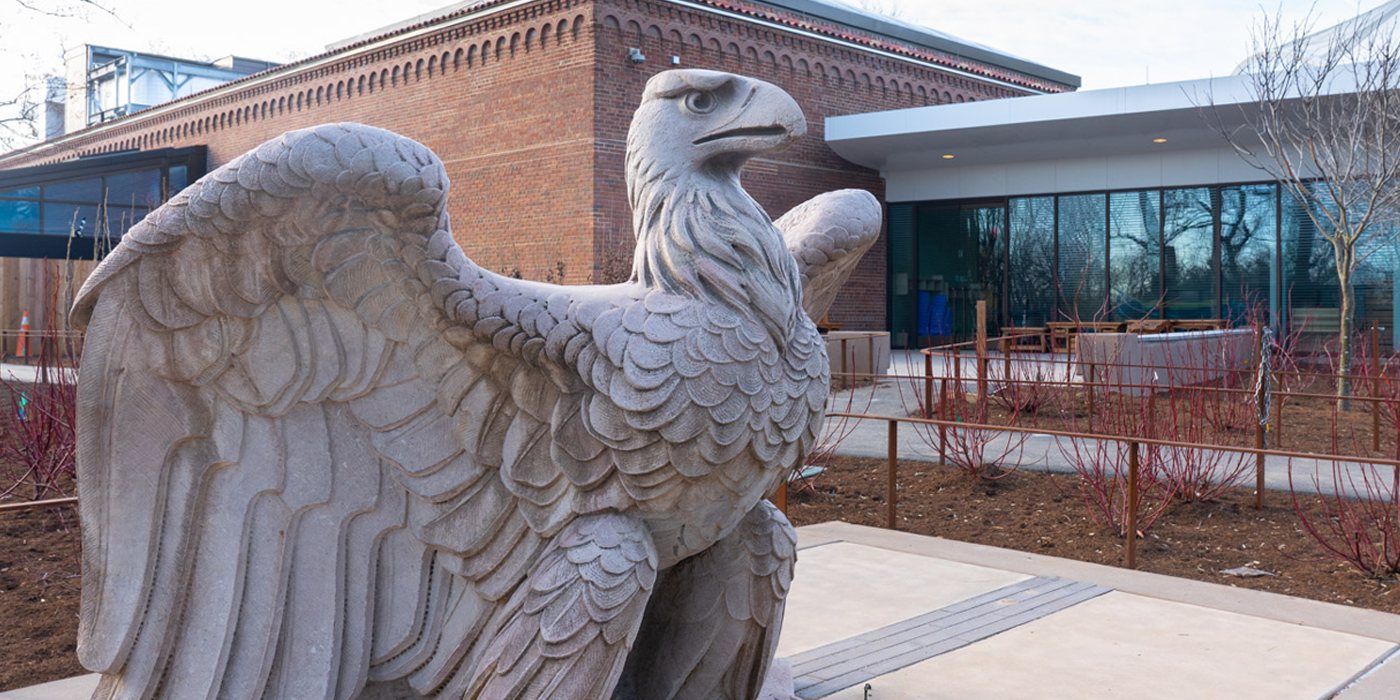 A concrete statue of a bald eagle perches proudly, wings spread, near the entrance of the Bird House.