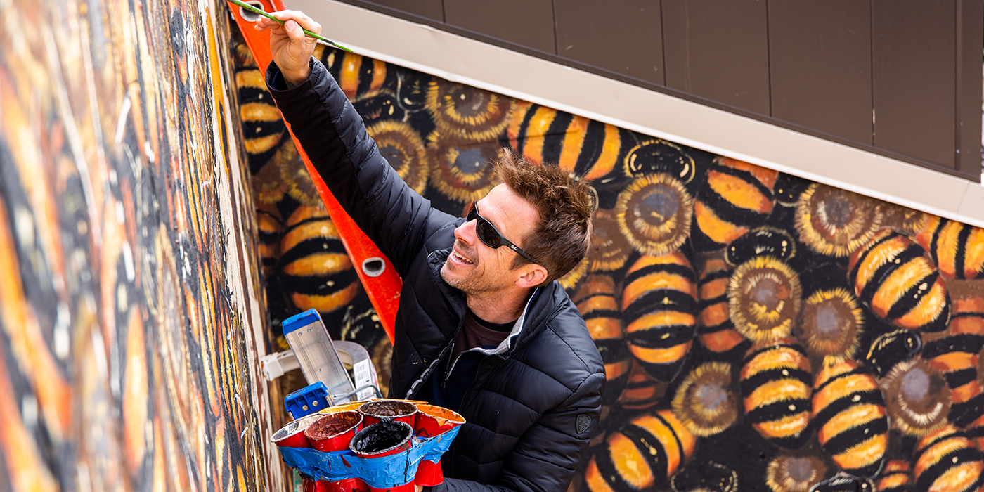 Artist Matthew Willey paints a bee mural on the Smithsonian's National Zoo's Great Ape House
