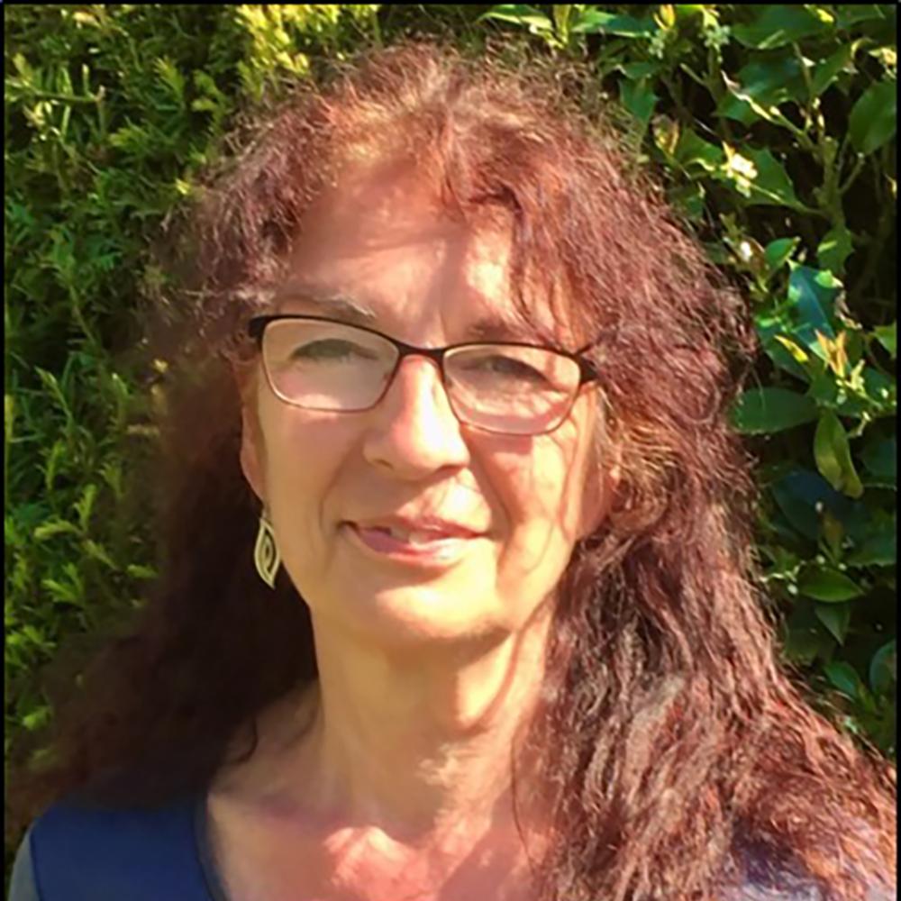 Headshot of a woman with glasses and long, red hair.