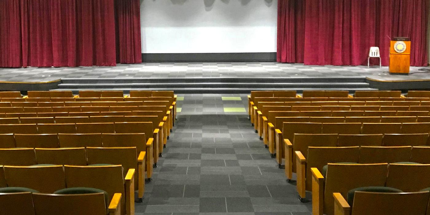 The view from the back of the Visitor Center Auditorium at the Smithsonian's National Zoo. There is an aisle down the center with auditorium seats on either side and a stage at the front